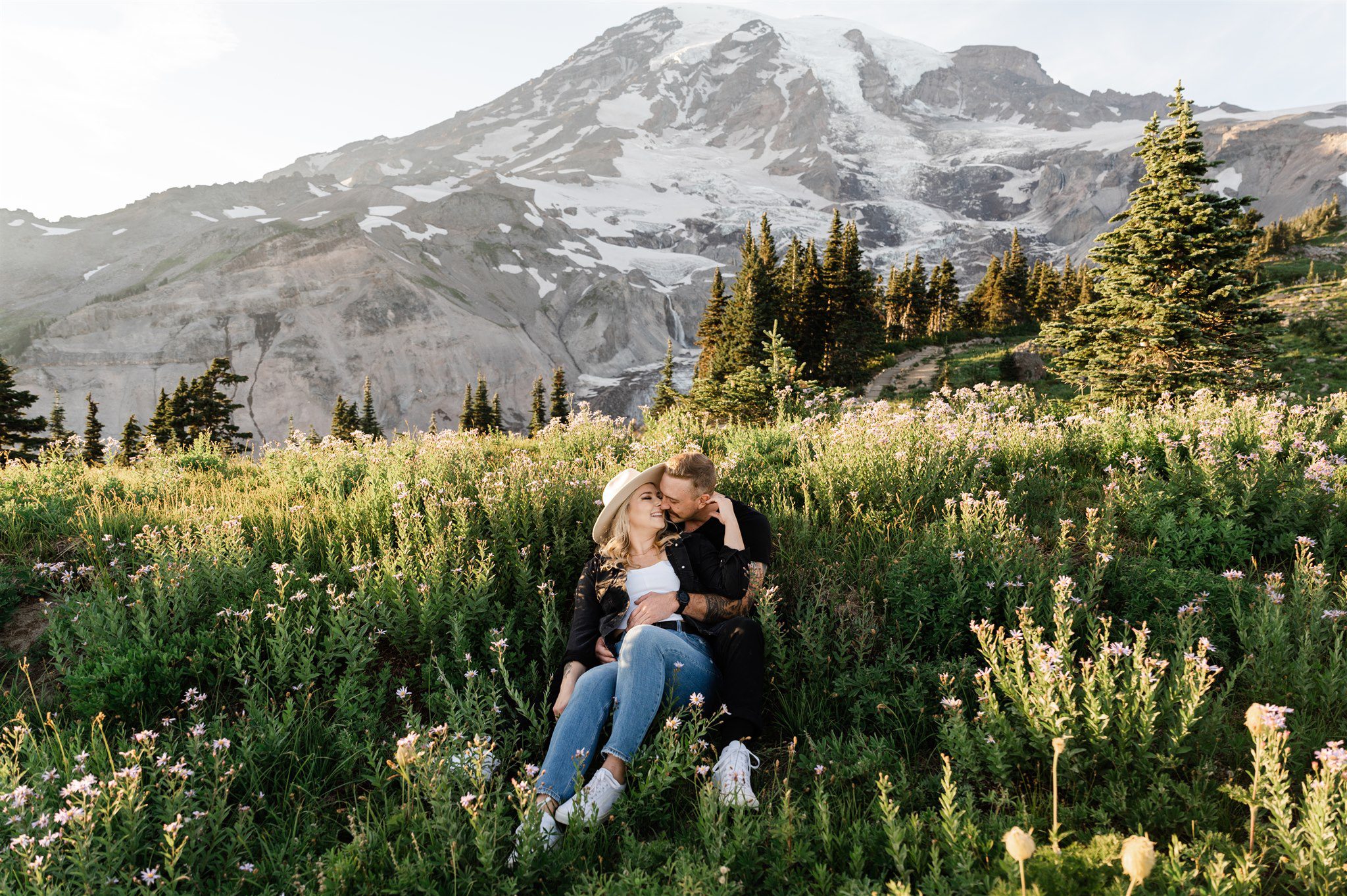 Couple sitting in wildflowers with Mt. Rainer in the background