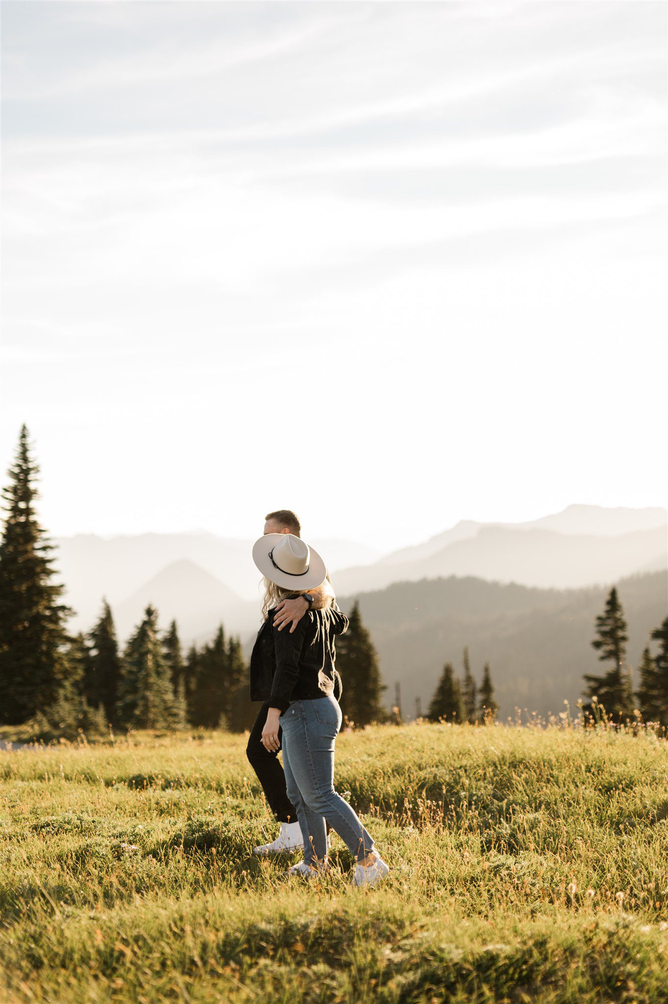 Couple walking with pine trees in the background