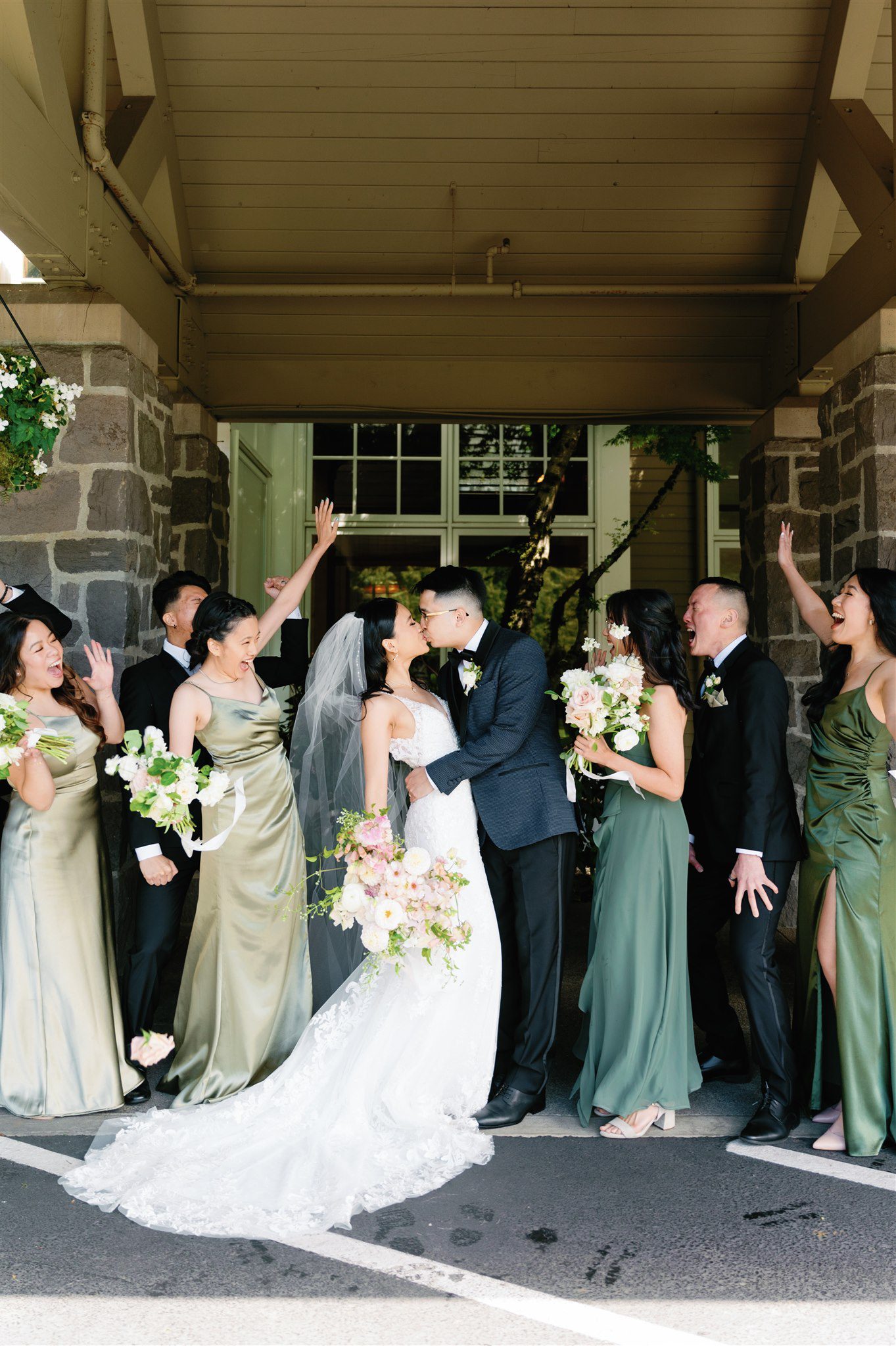 Bridal party cheering as bride and groom kiss