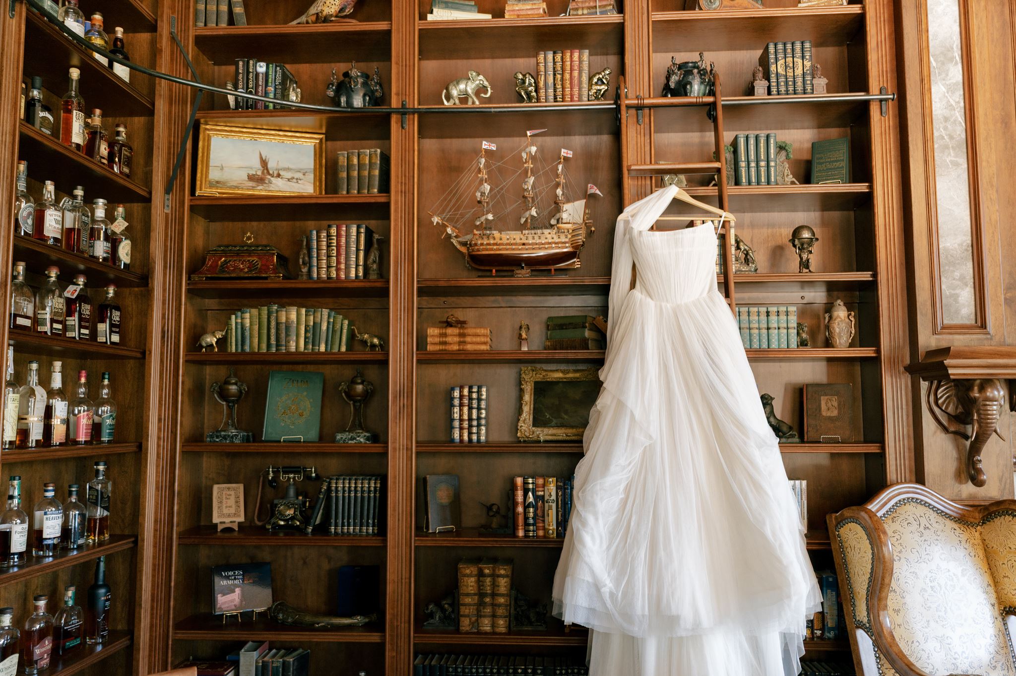 Wedding dress hung in a moody library at a private estate venue