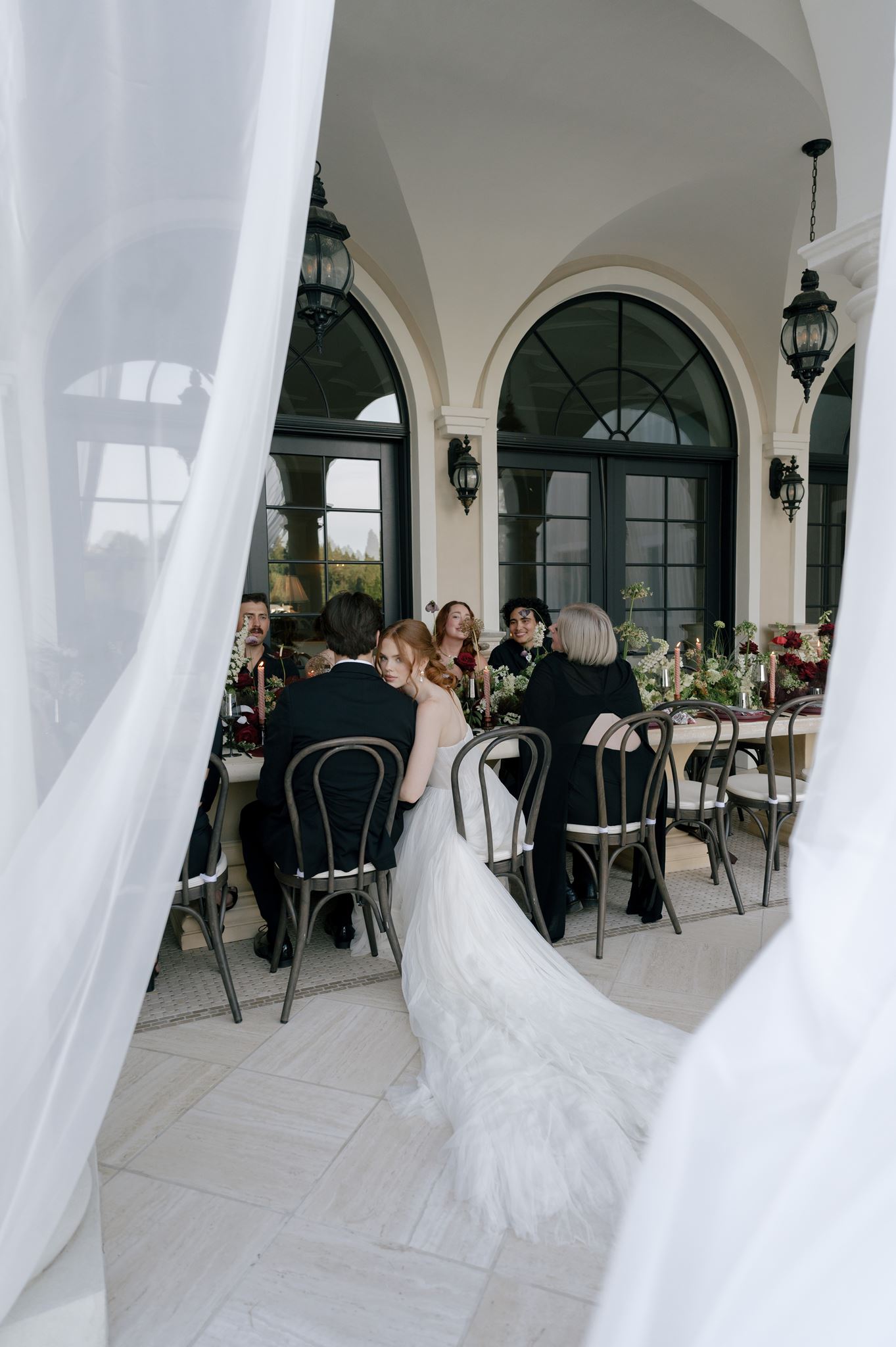 Bride and groom sitting with guests at their wedding reception at Palais de Leon