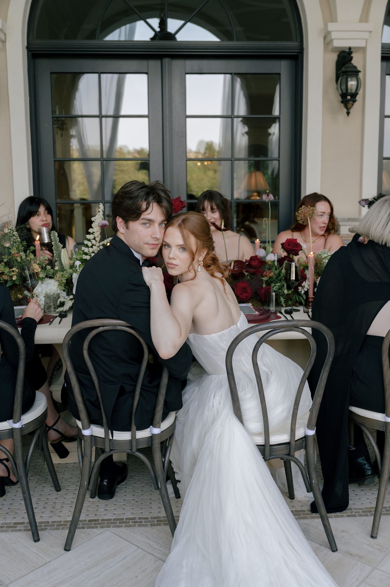 Bride and groom sitting with guests at their wedding reception at Palais de Leon