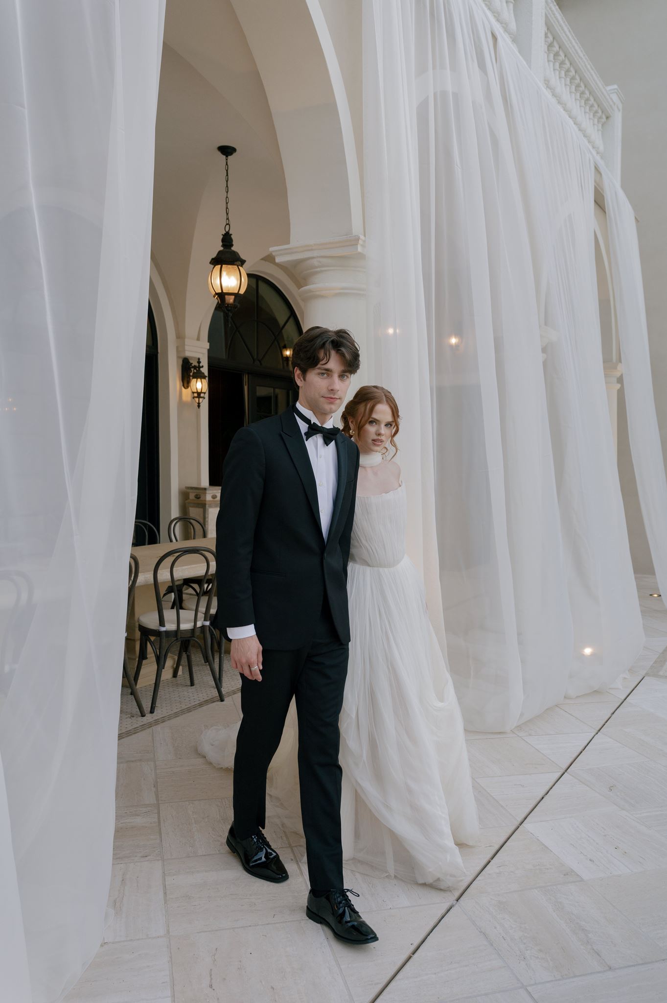 Bride and groom emerging from flowy draping on a terrace